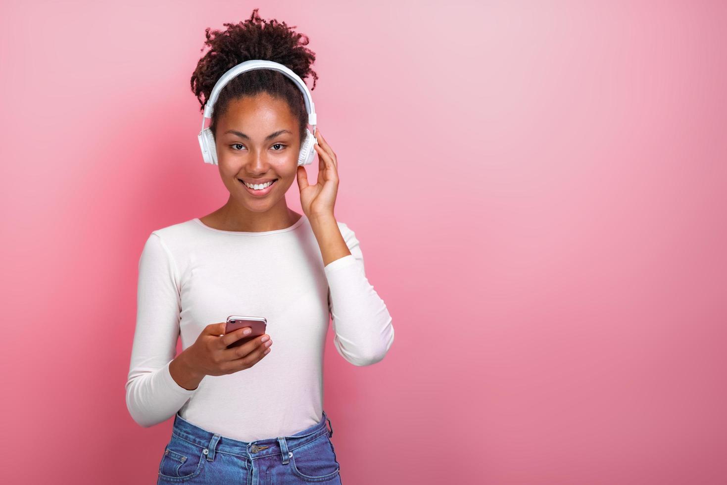 retrato de uma menina com fones de ouvido e segurando um telefone celular, olhando para a câmera - imagem foto