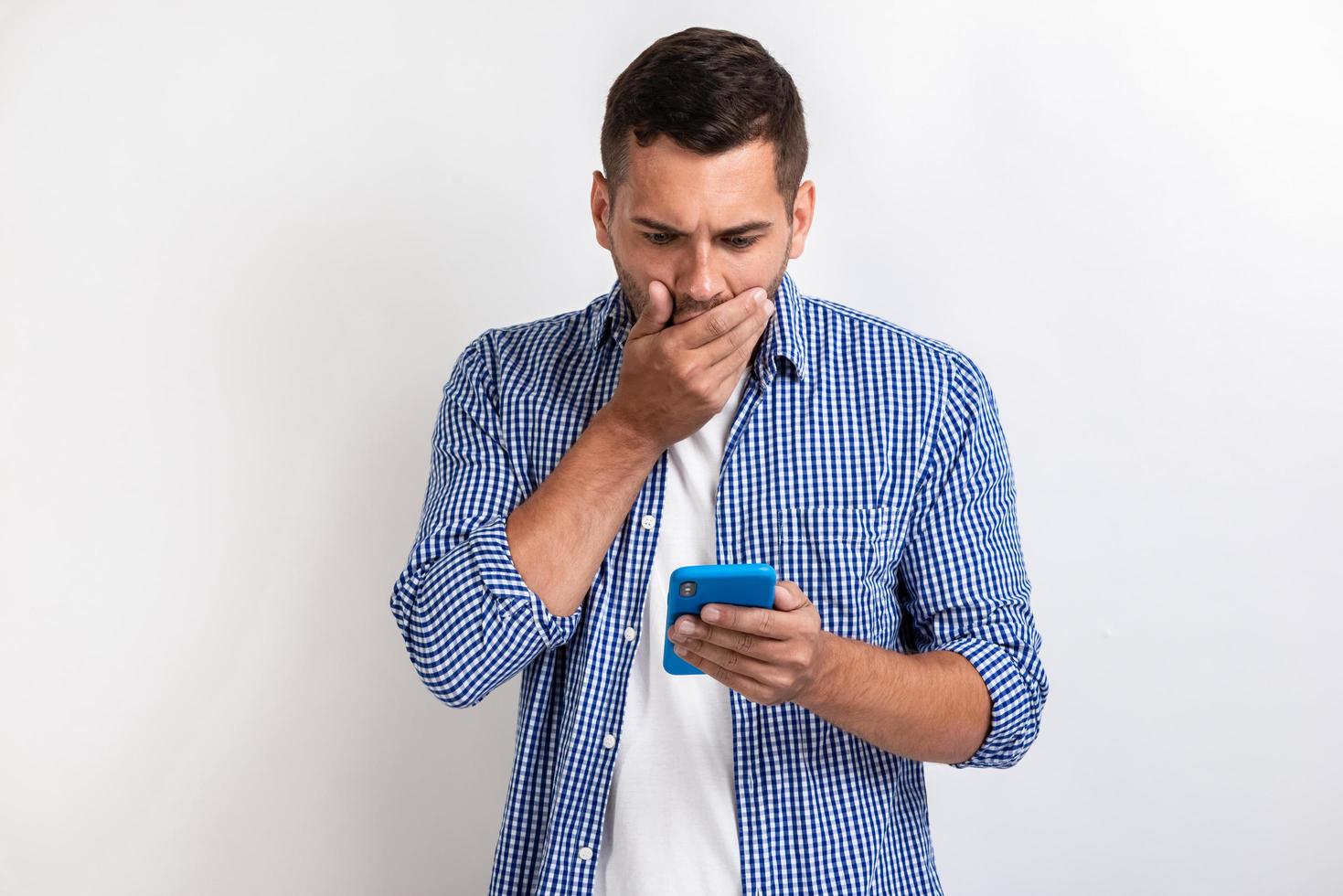 homem surpreso em pé com um smartphone nas mãos e olhando para a tela.- imagem foto