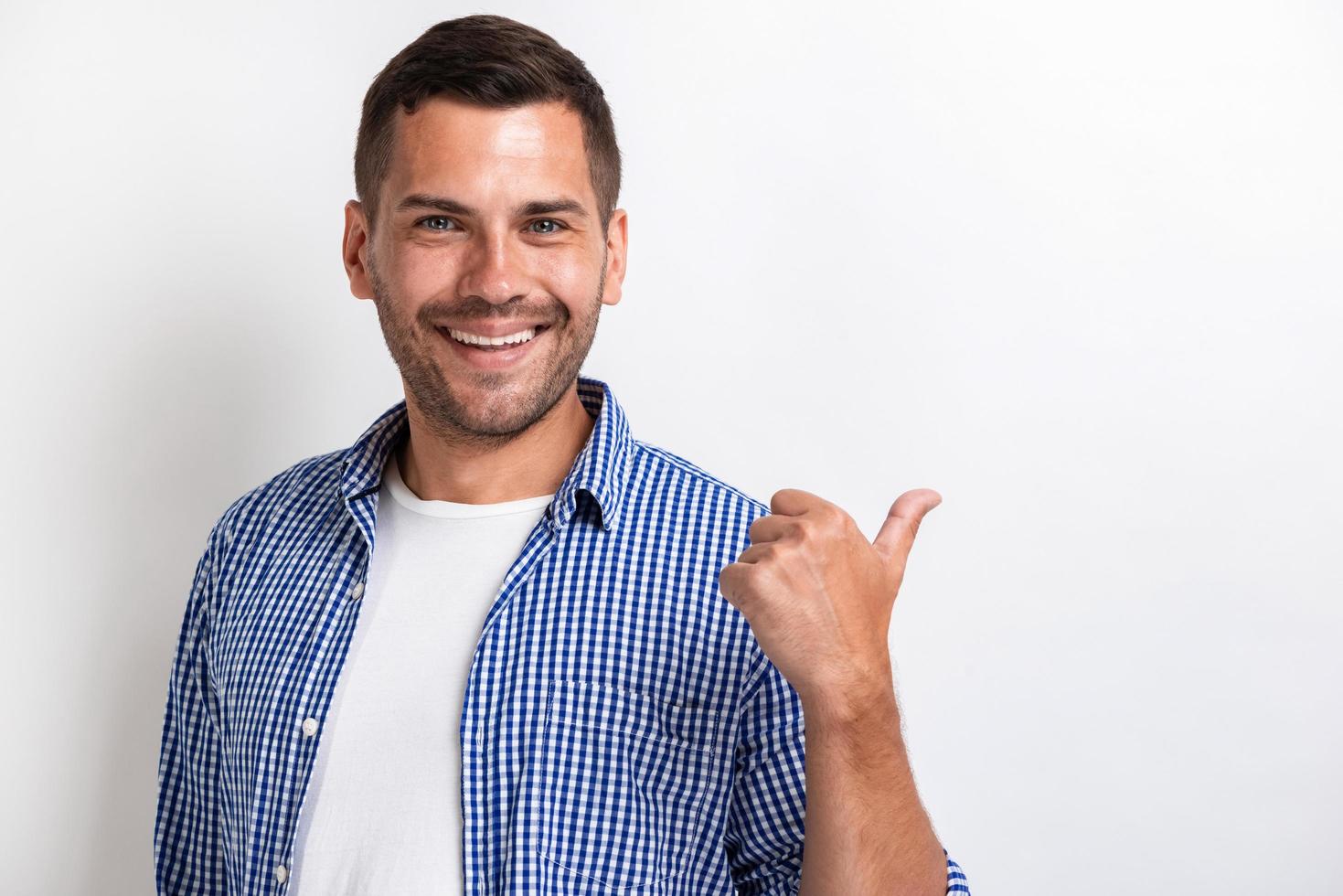 homem bonito e feliz apontando para trás com o dedo grande e olhando para a câmera.- imagem foto