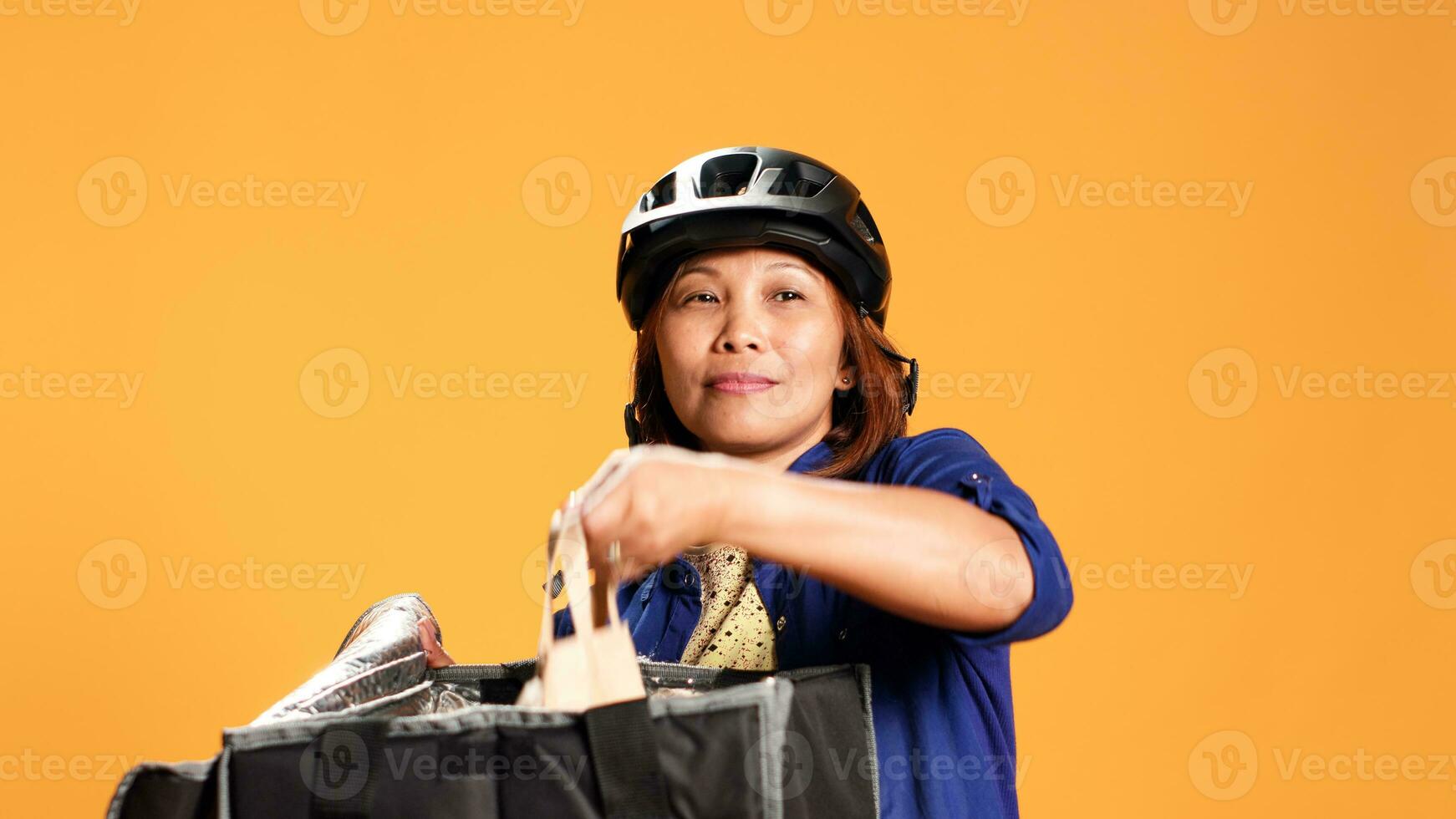 fechar acima tiro do Leve embora Entrega trabalhador preparando Comida ordem enquanto esperando para cliente para responda porta. correio isolado sobre estúdio fundo levando refeição saco Fora do profissional térmico mochila foto