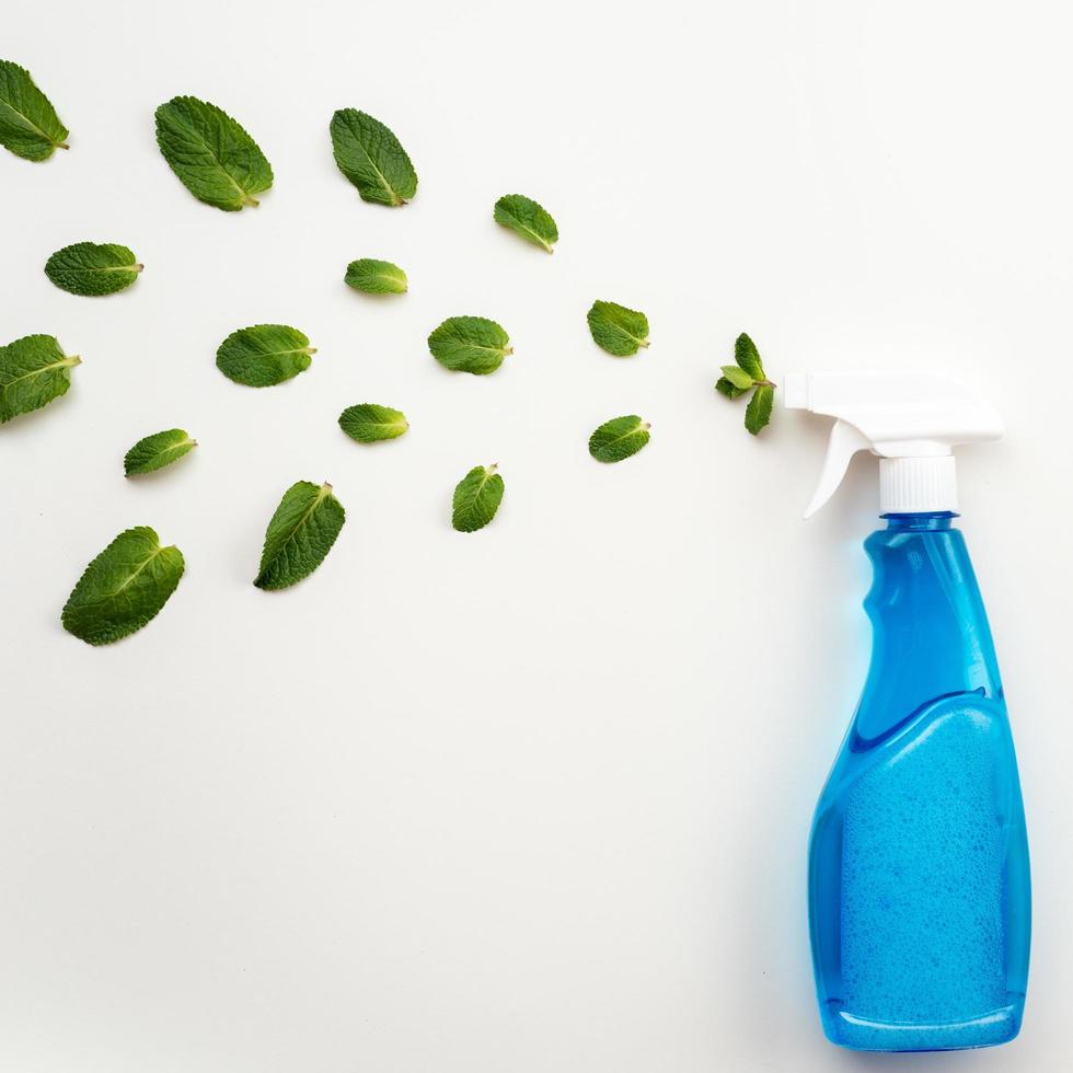 Frasco de detergente azul com tampa branca em um fundo branco borrife folhas de hortelã frescas foto