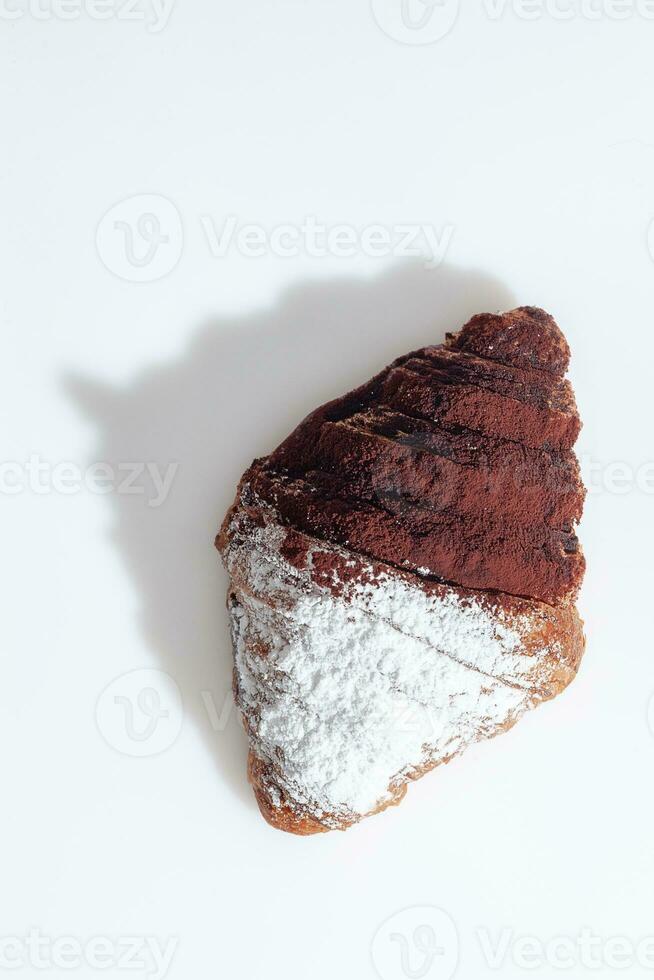 chocolate croissant borrifado com em pó açúcar e cacau em branco superfície foto