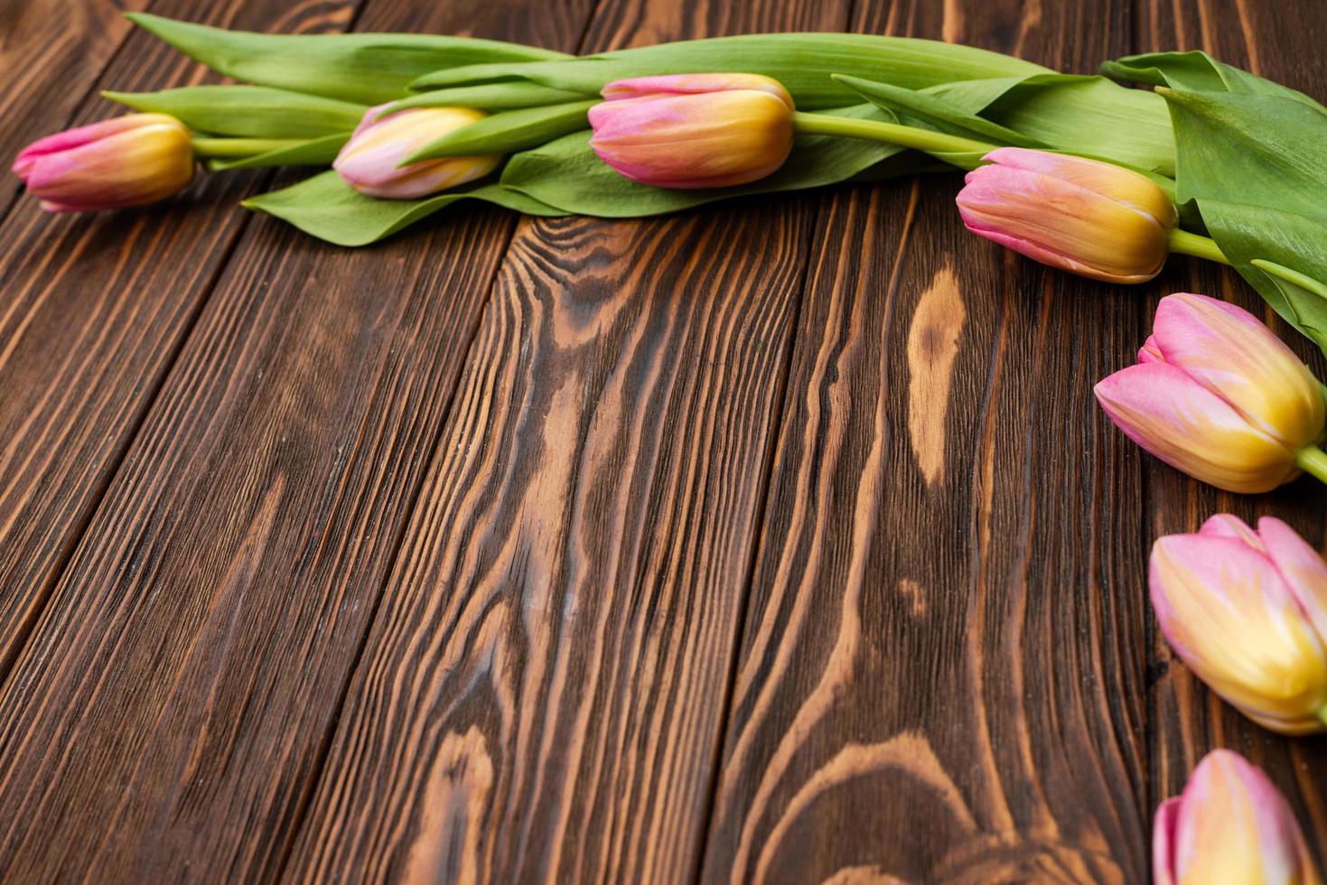 tulipas nas tábuas de madeira da mesa. cartão para o dia das mães, a Páscoa. copie o espaço foto