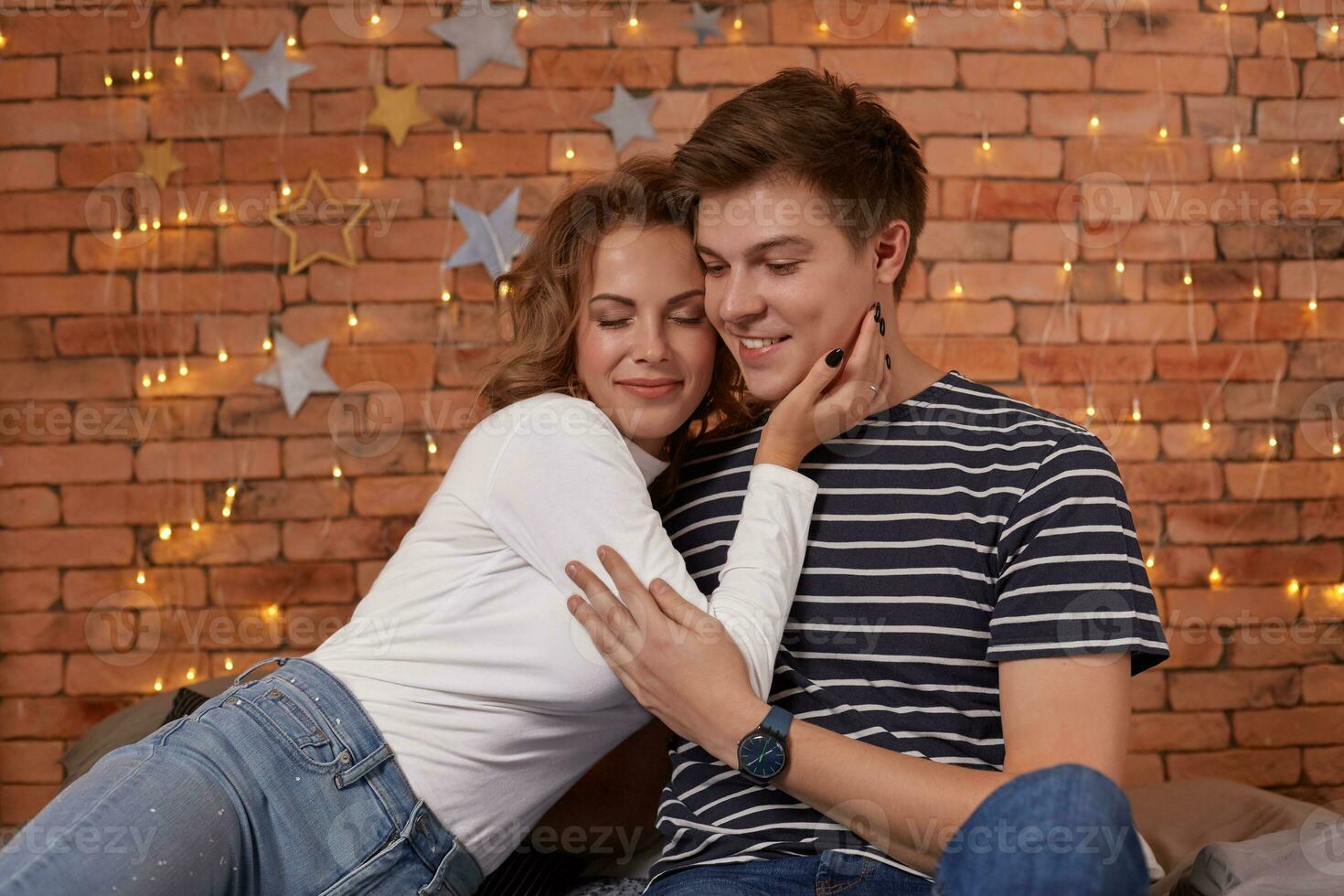 feliz amoroso casal relaxante em cama às lar, jovem mulher tocante sorridente bonito homem face, olhando dentro a olhos. foto