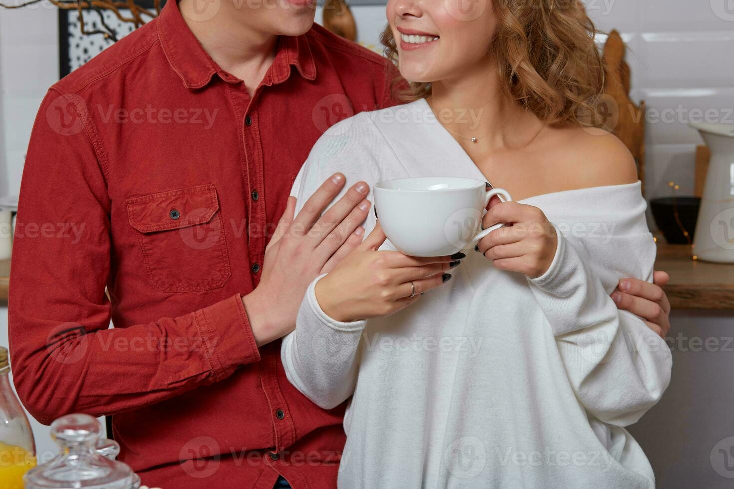 feliz jovem adorável casal em cozinha abraçando cada outro. elas apreciar bebendo café foto