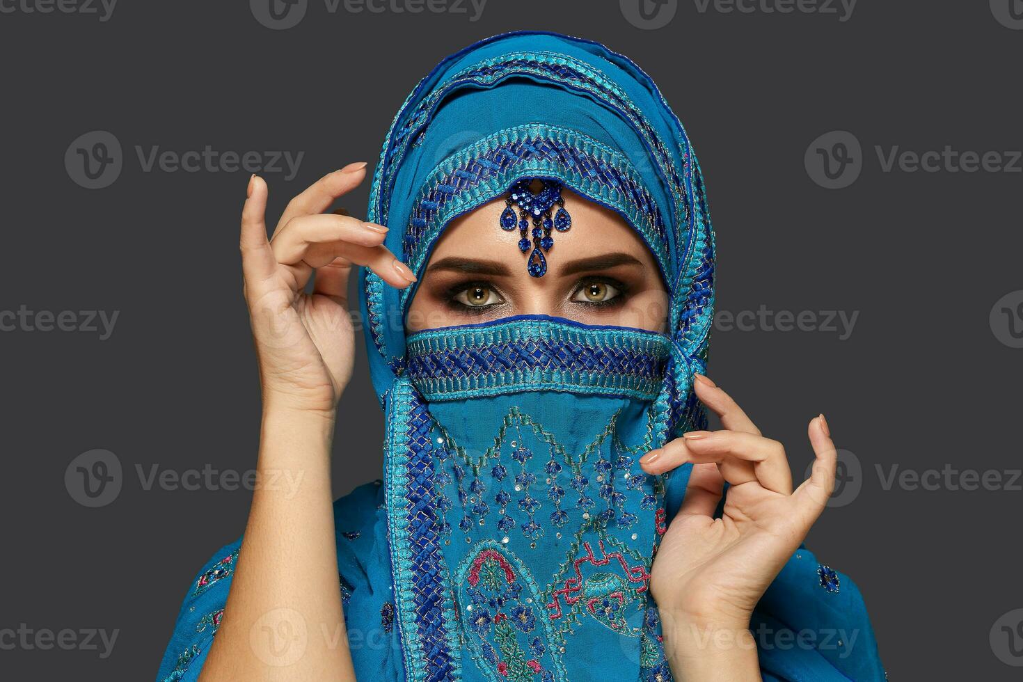 estúdio tiro do uma jovem lindo mulher vestindo a azul hijab decorado com lantejoulas e joia. árabe estilo. foto