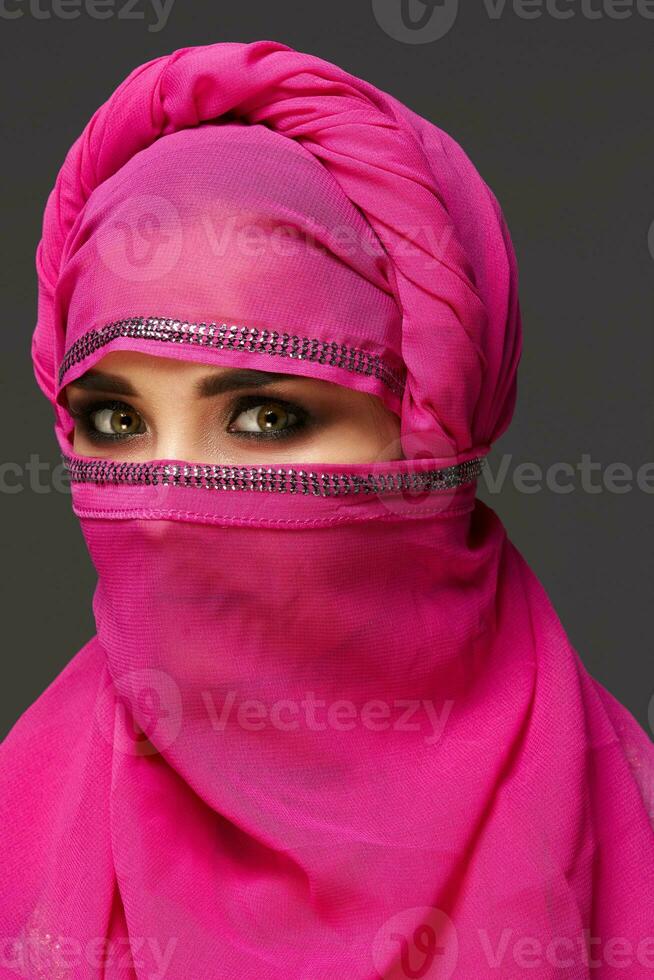 fechar-se tiro do uma jovem encantador mulher vestindo a Rosa hijab decorado com lantejoulas. árabe estilo. foto