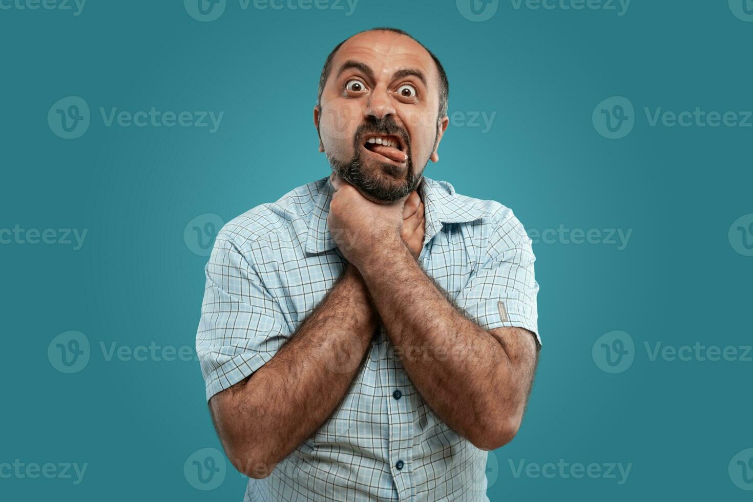 fechar-se retrato do uma moreno meia idade homem com barba, vestido dentro uma luz xadrez camisa e posando contra uma azul fundo. foto