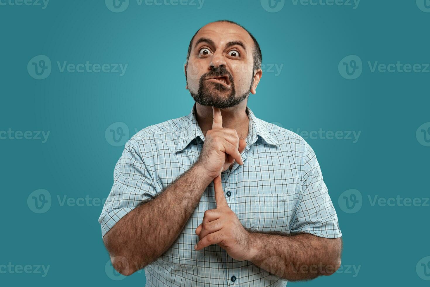 fechar-se retrato do uma moreno meia idade homem com barba, vestido dentro uma luz xadrez camisa e posando contra uma azul fundo. foto