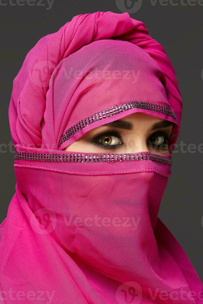 fechar-se tiro do uma jovem encantador mulher vestindo a Rosa hijab decorado com lantejoulas. árabe estilo. foto