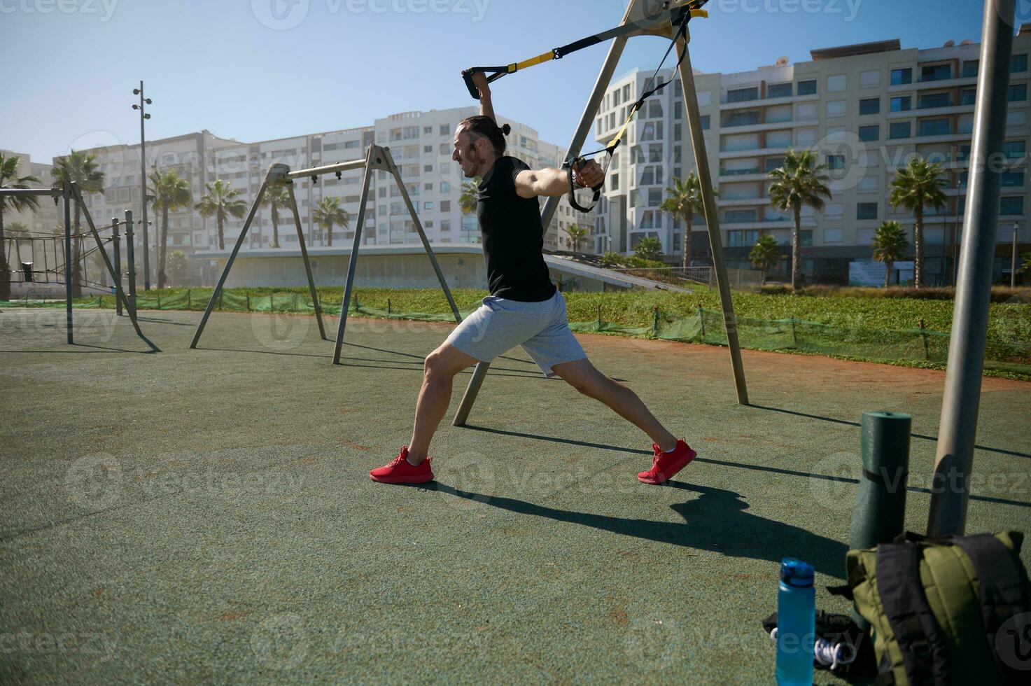 ativo determinado masculino atleta dentro Esportes vestir, usando suspensão ginástica correias, realizando peso corporal Treinamento ao ar livre foto