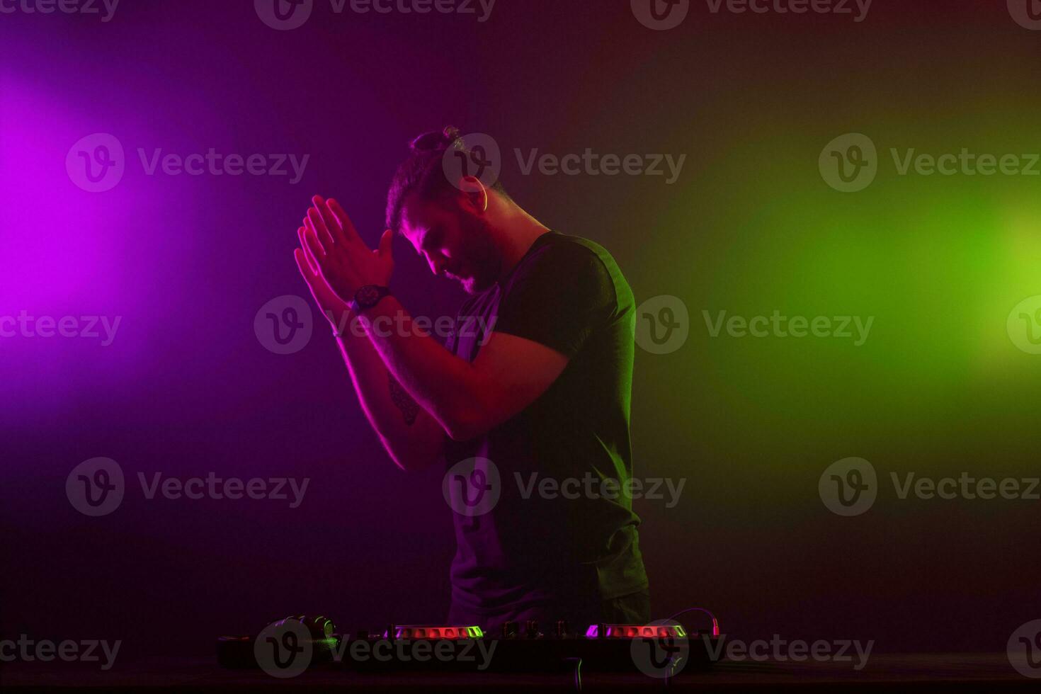 dj às trabalhos mistura som em dela decks às uma festa ou noite clube com colorida fumaça luz fundo foto