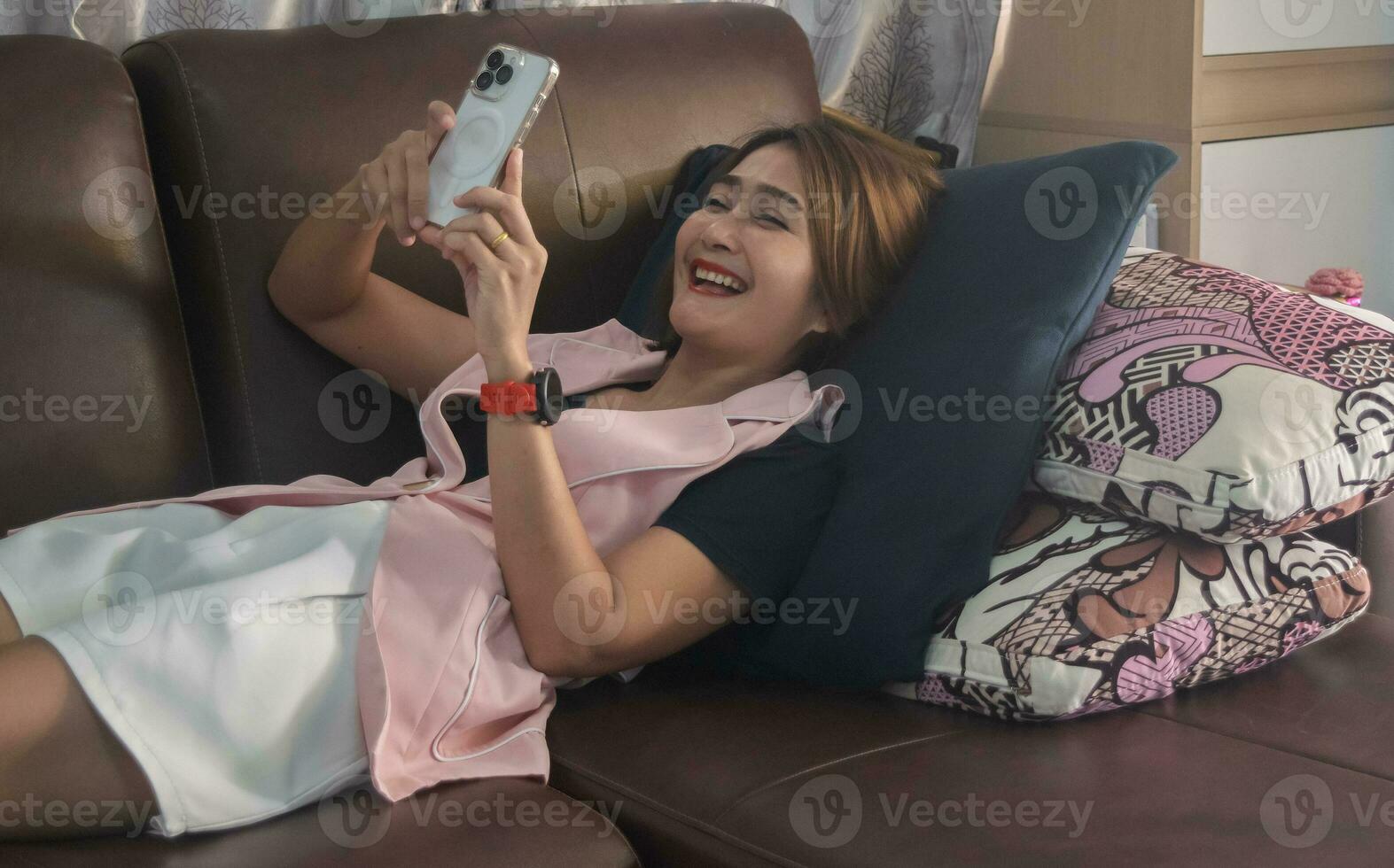 mulher dormir em a sofá usando Smartphone vídeo ligar com amigo finais de semana em social mídia, assistir filmes e ouço para música às casa, estilo de vida conceitos foto