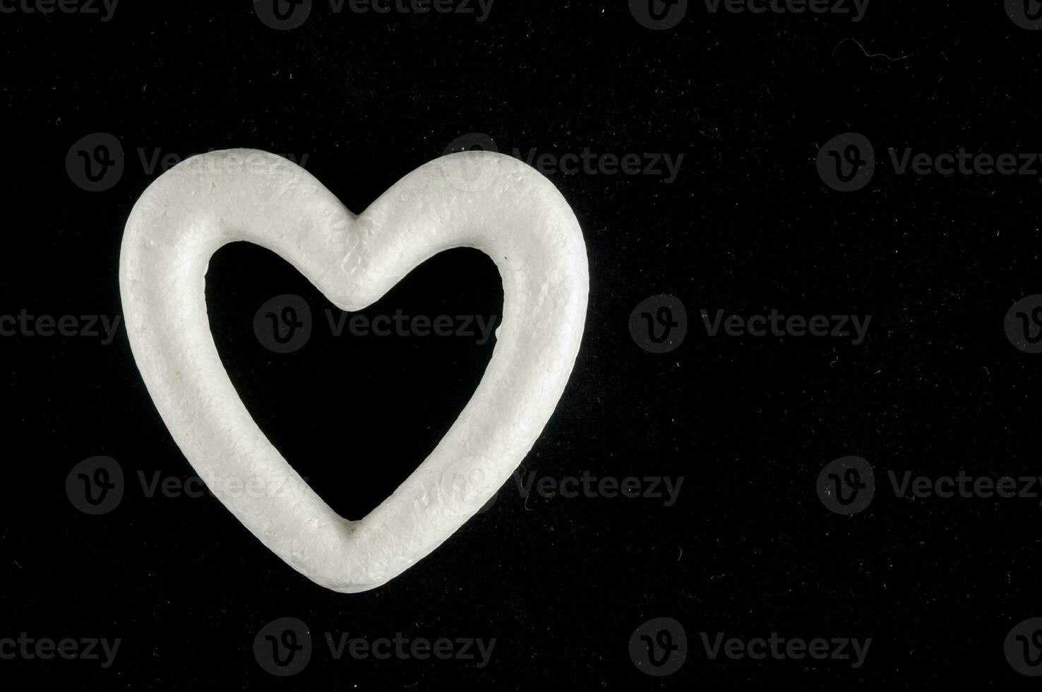 uma branco coração em forma objeto em uma Preto fundo foto