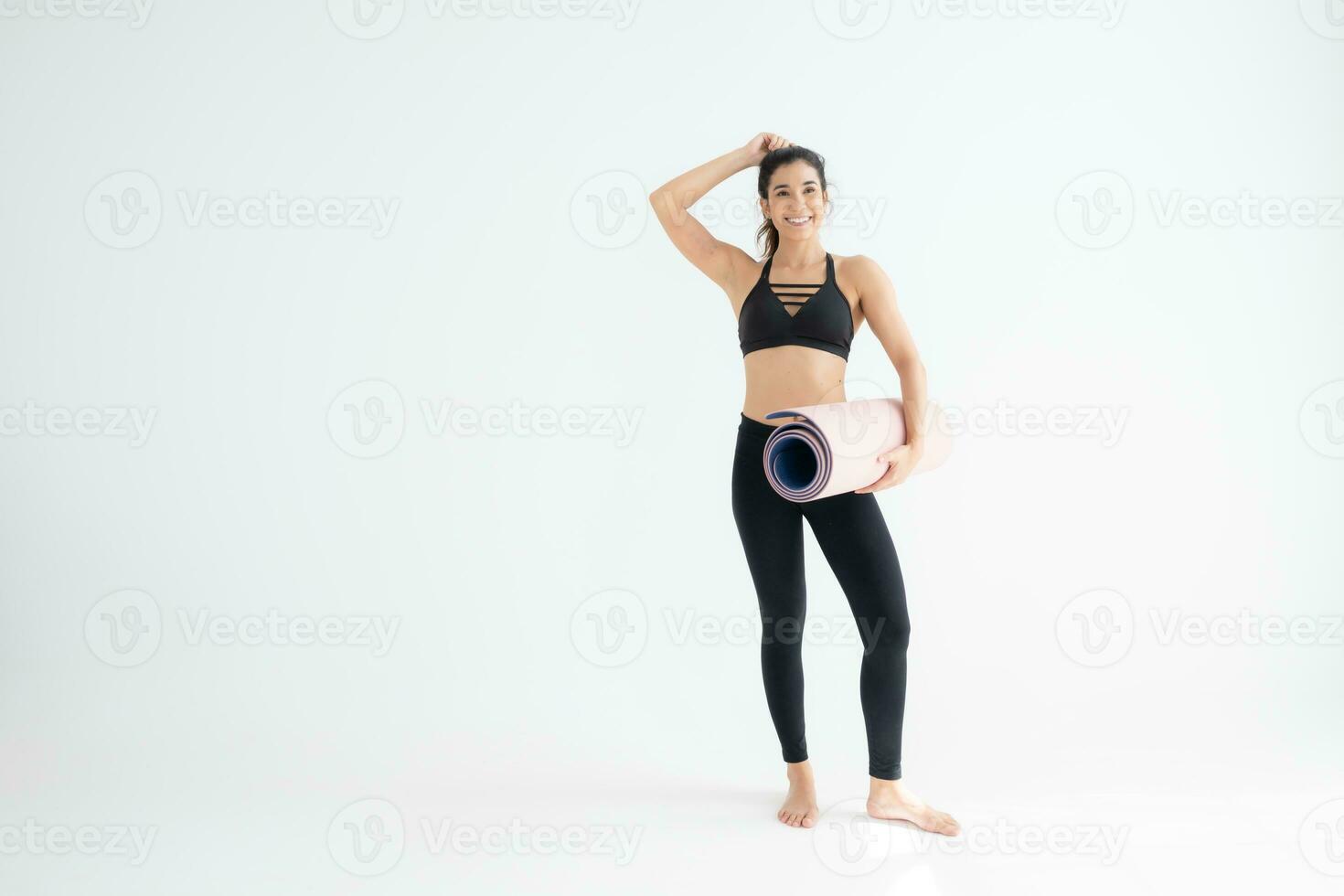 cheio comprimento retrato do uma jovem mulher segurando ioga esteira isolado em branco fundo foto