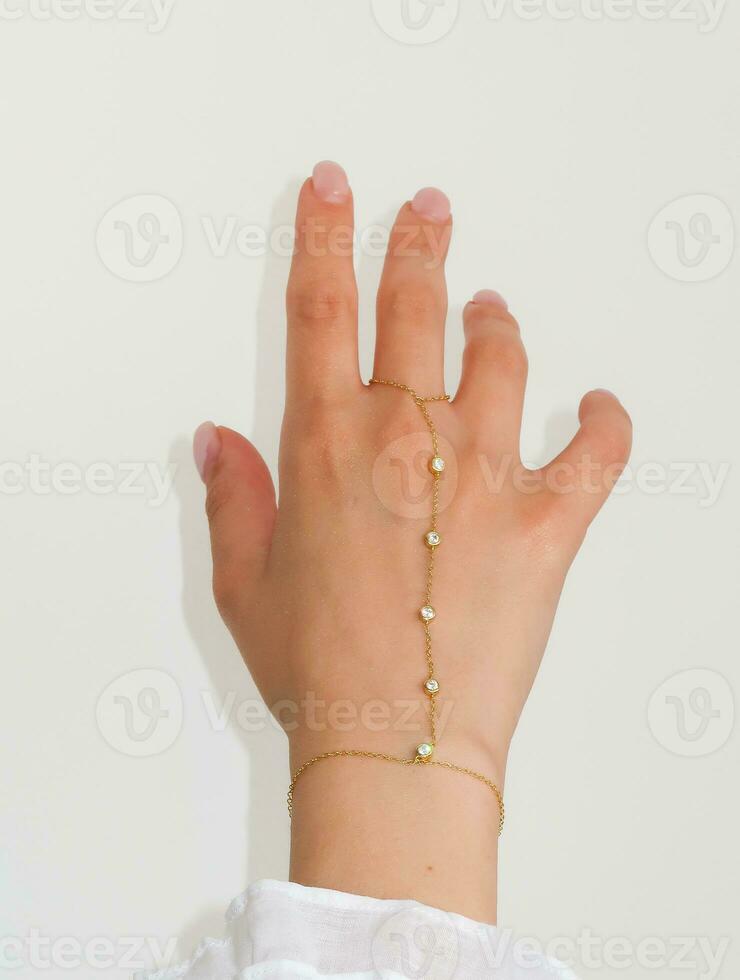 mulher mão pulso vestindo dourado mão cadeia conjunto contra uma branco fundo. foto