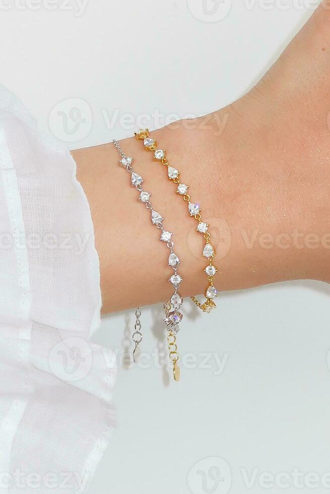 mulher pulso vestindo zircão brilhar pulseiras conjunto contra uma branco fundo. foto