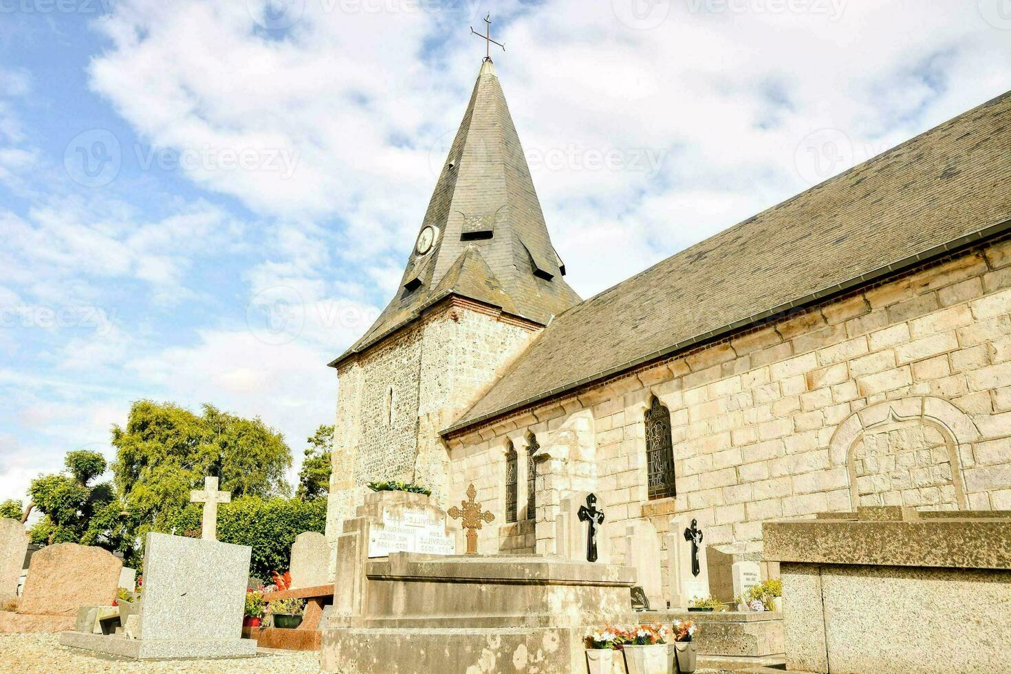uma Igreja com uma campanário e uma cemitério foto