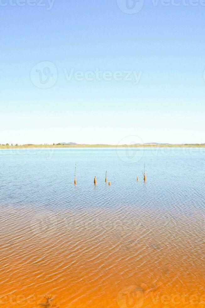 uma lago com laranja água e uma azul céu foto