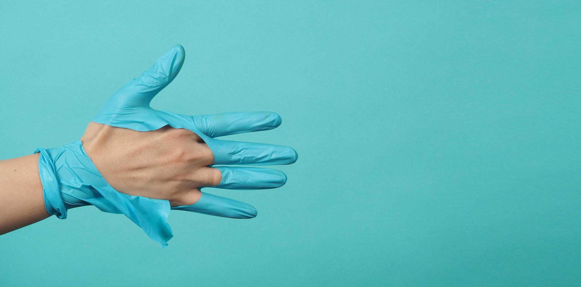 feche a mão usando luvas médicas rasgadas ou luvas de borracha rasgadas na cor azul e verde ou azul tiffany background.monotone coclor. foto