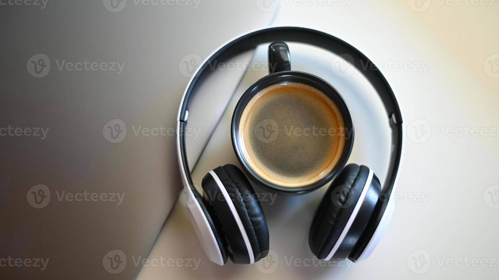 vista superior da caneca de café com laptop e fone de ouvido colocado sobre uma mesa em um café, lugar de caneca de café no fone de ouvido. foto