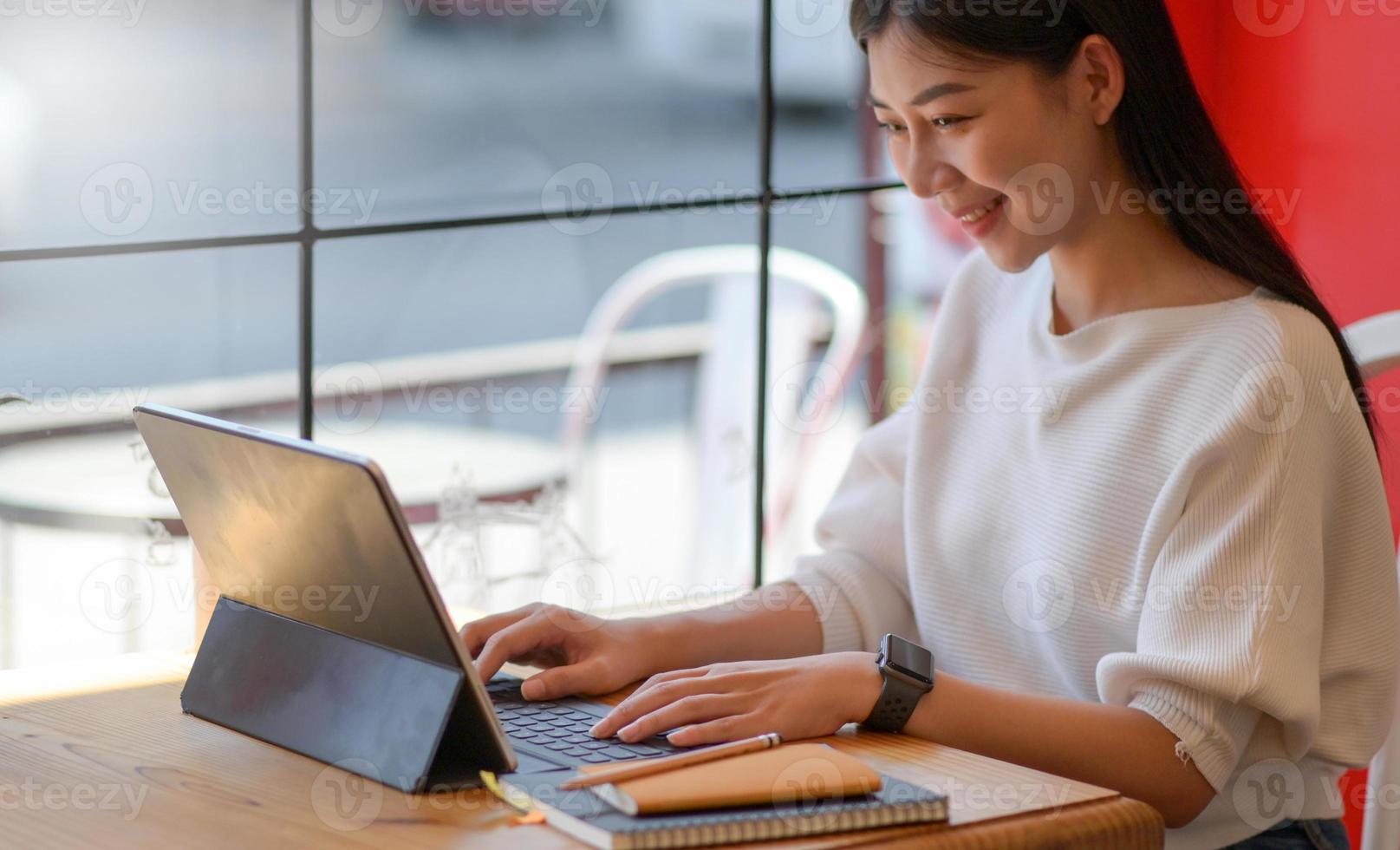 uma jovem está operando um laptop em um café com uma expressão sorridente. foto