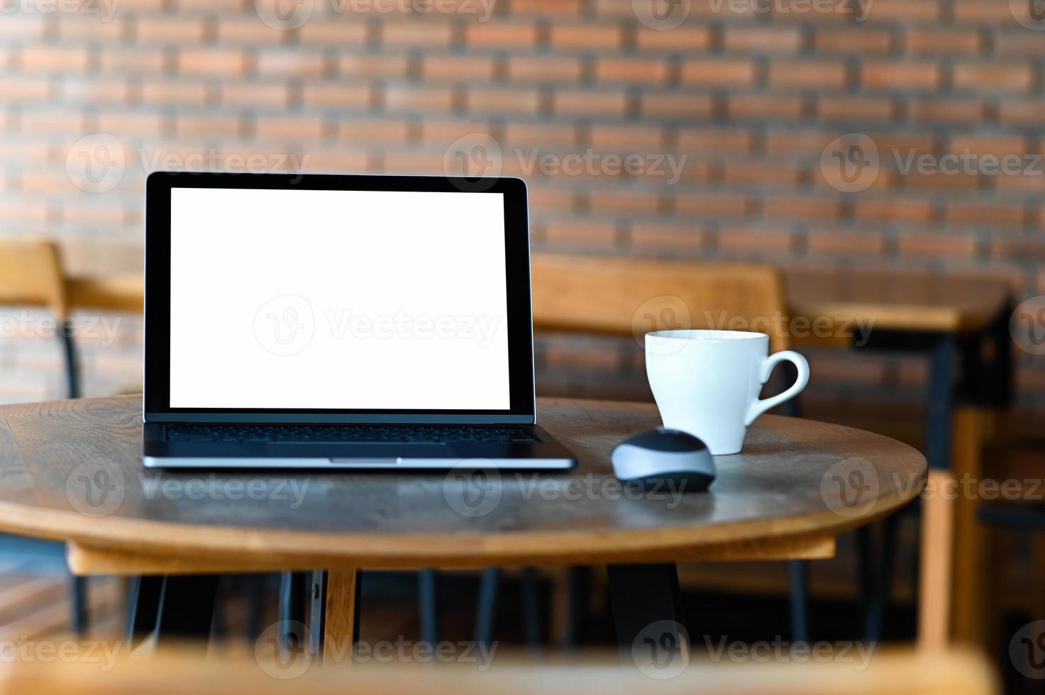 laptop de tela em branco de maquete com café na mesa, retirado da frente. foto