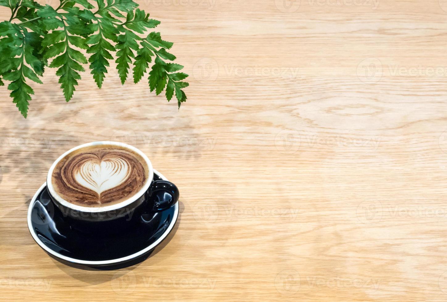 xícara de café na mesa de madeira com folha de samambaia foto
