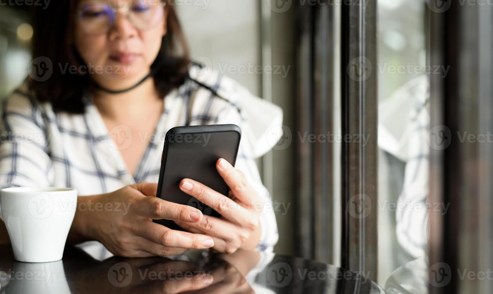mulher asiática usando smartphone na cafeteria. foto