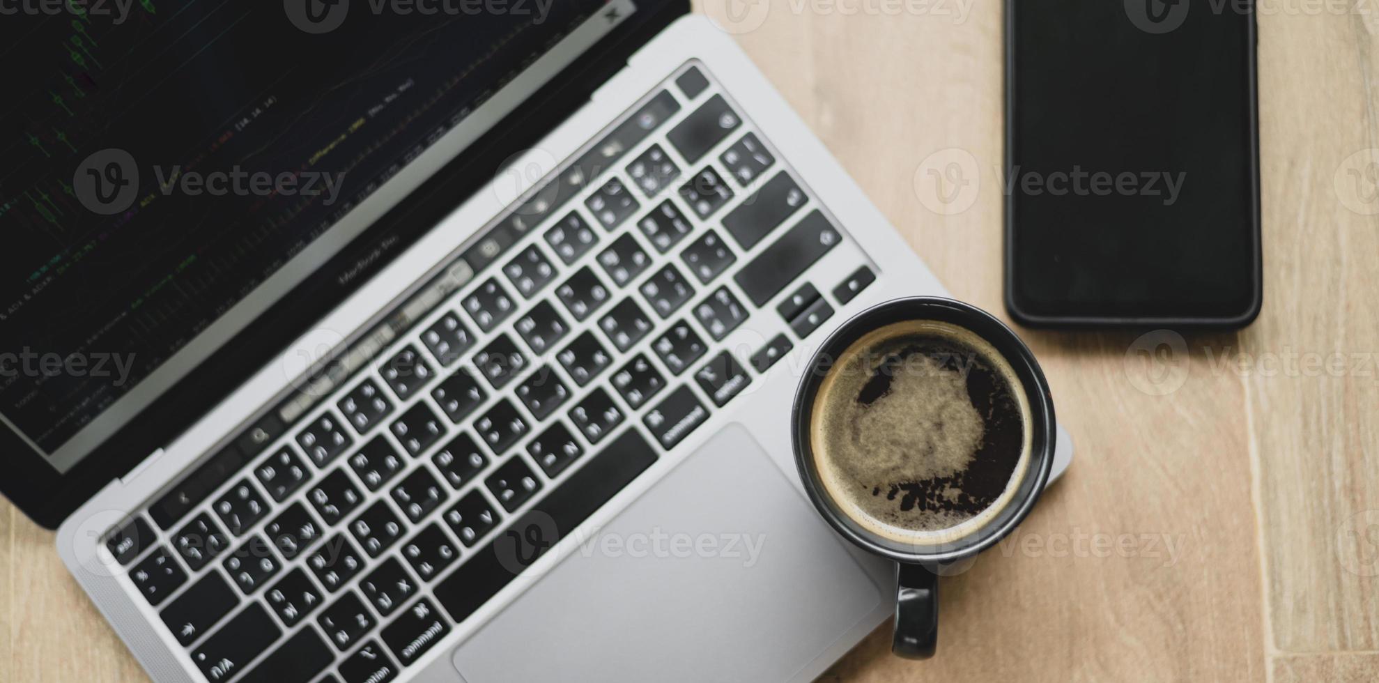 caneca de café colocada no laptop com gráfico de ações na tela, vista superior um tiro. foto