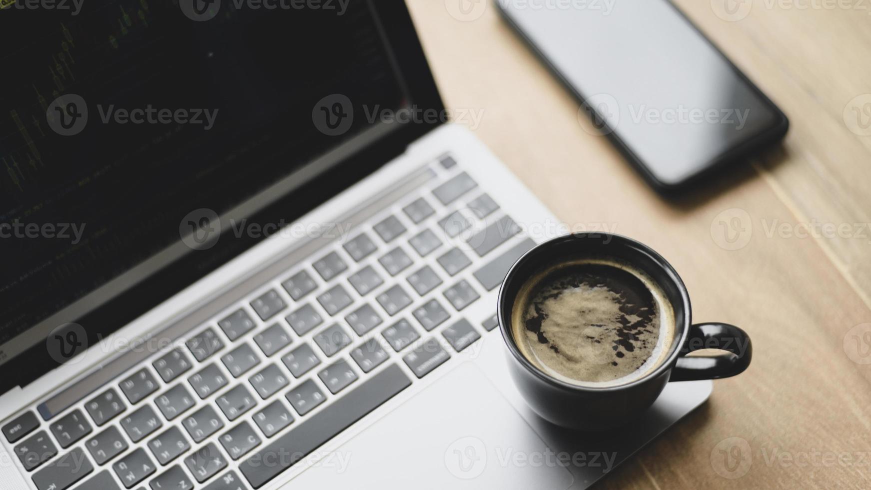 caneca de café colocada no laptop com gráfico de ações na tela, vista superior um tiro. foto