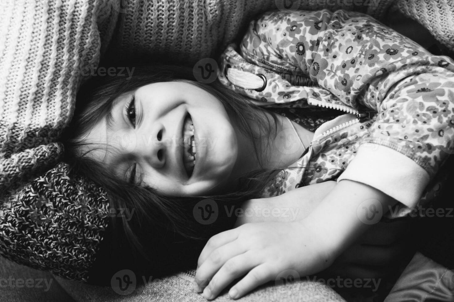 menina mostra dentes deitado em a caído mãe foto