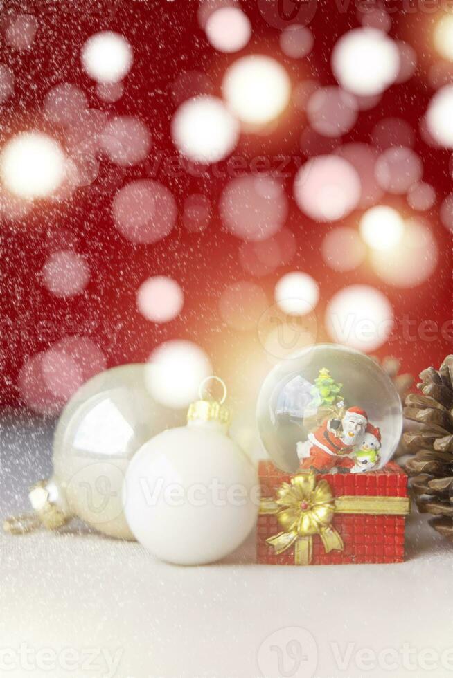 Natal bolas, santa claus dentro uma neve globo, e pinho cones em uma cor de creme pano, conjunto contra uma vermelho fundo e requintado bokeh. Novo ano celebração atmosfera, sobre do importante dia. foto