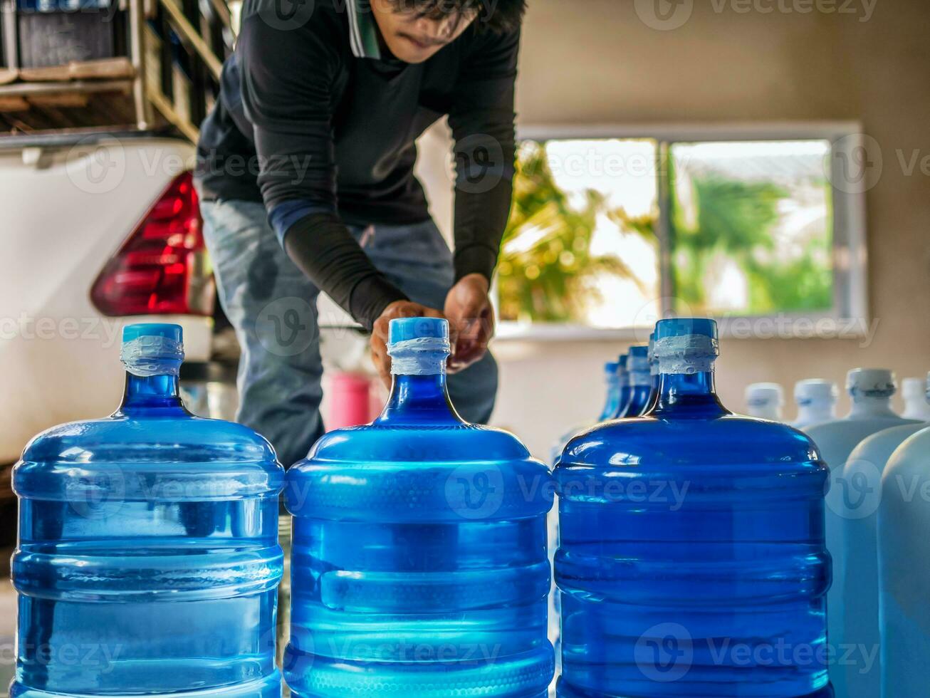 bebendo água Claro e limpar \ limpo dentro azul galão arranjado dentro uma linha preparar para lift para dentro a costas do uma transporte caminhão purificado bebendo água dentro a Produção linha pequeno o negócio foto