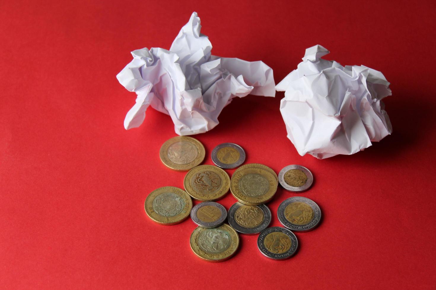 folhas de papel amassadas e moedas mexicanas em fundo vermelho foto