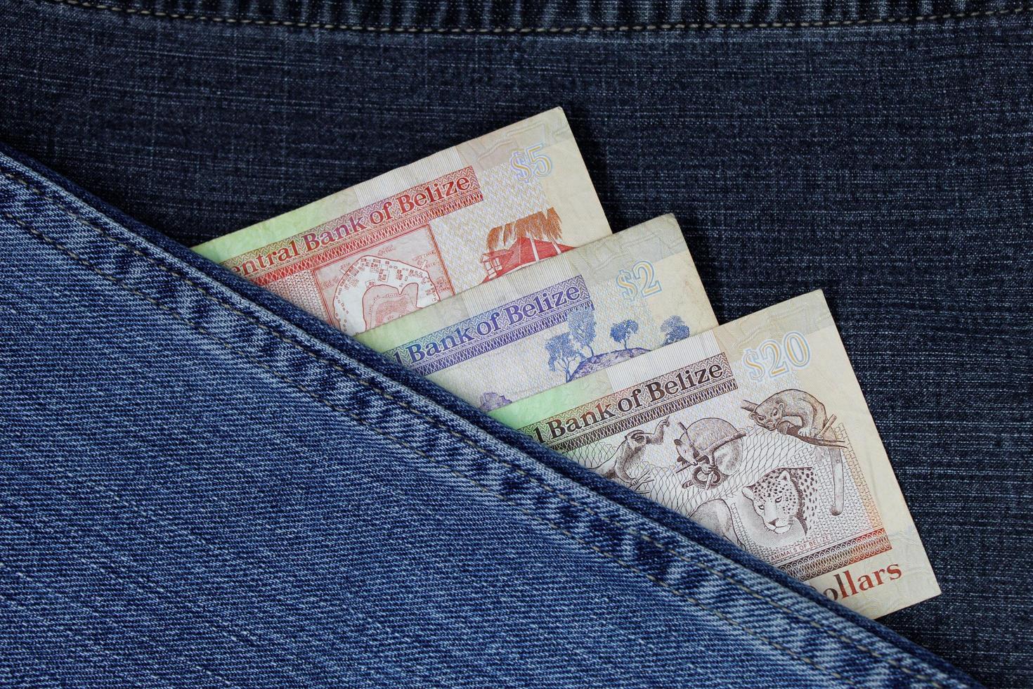 notas de banco belize de denominações diferentes entre tecido jeans azul foto