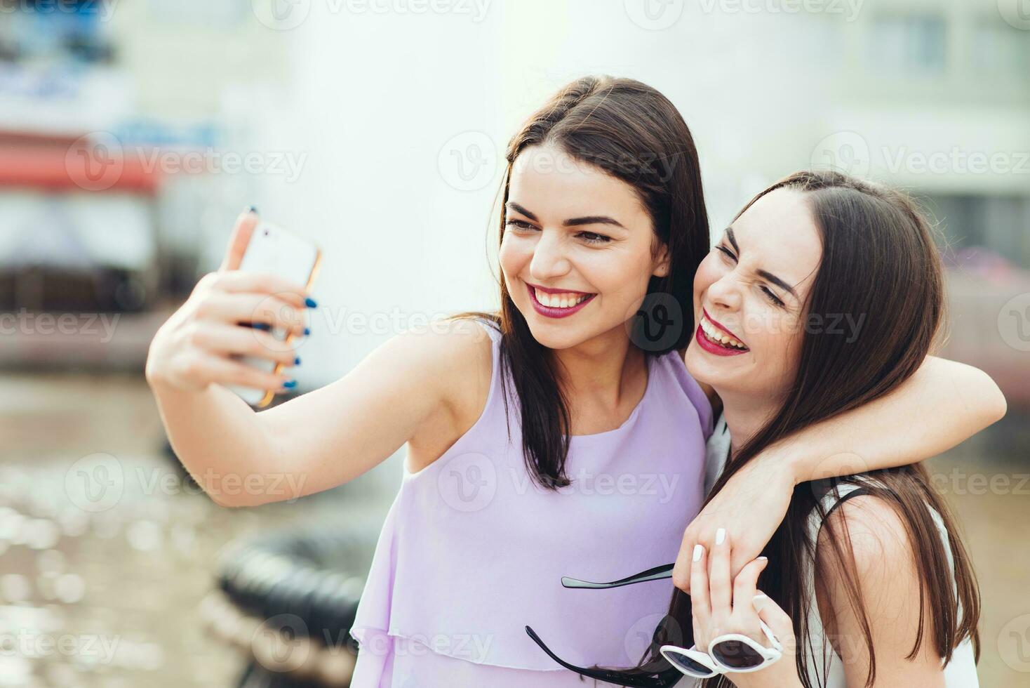 dois lindo irmãs Faz selfie em a rua foto