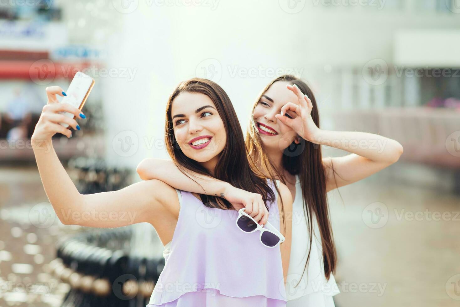 dois lindo irmãs Faz selfie em a rua foto