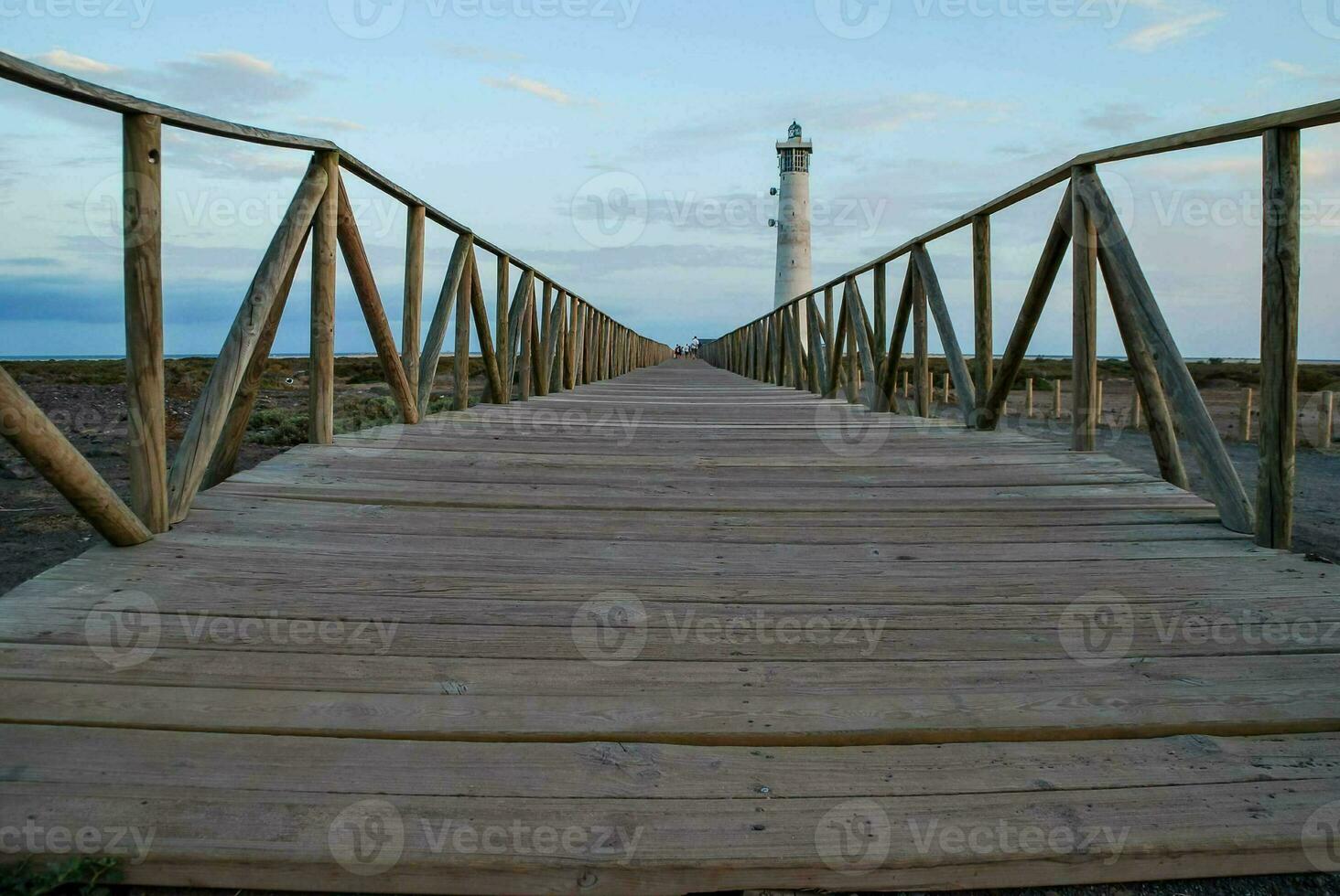 uma de madeira ponte conduz para uma farol foto