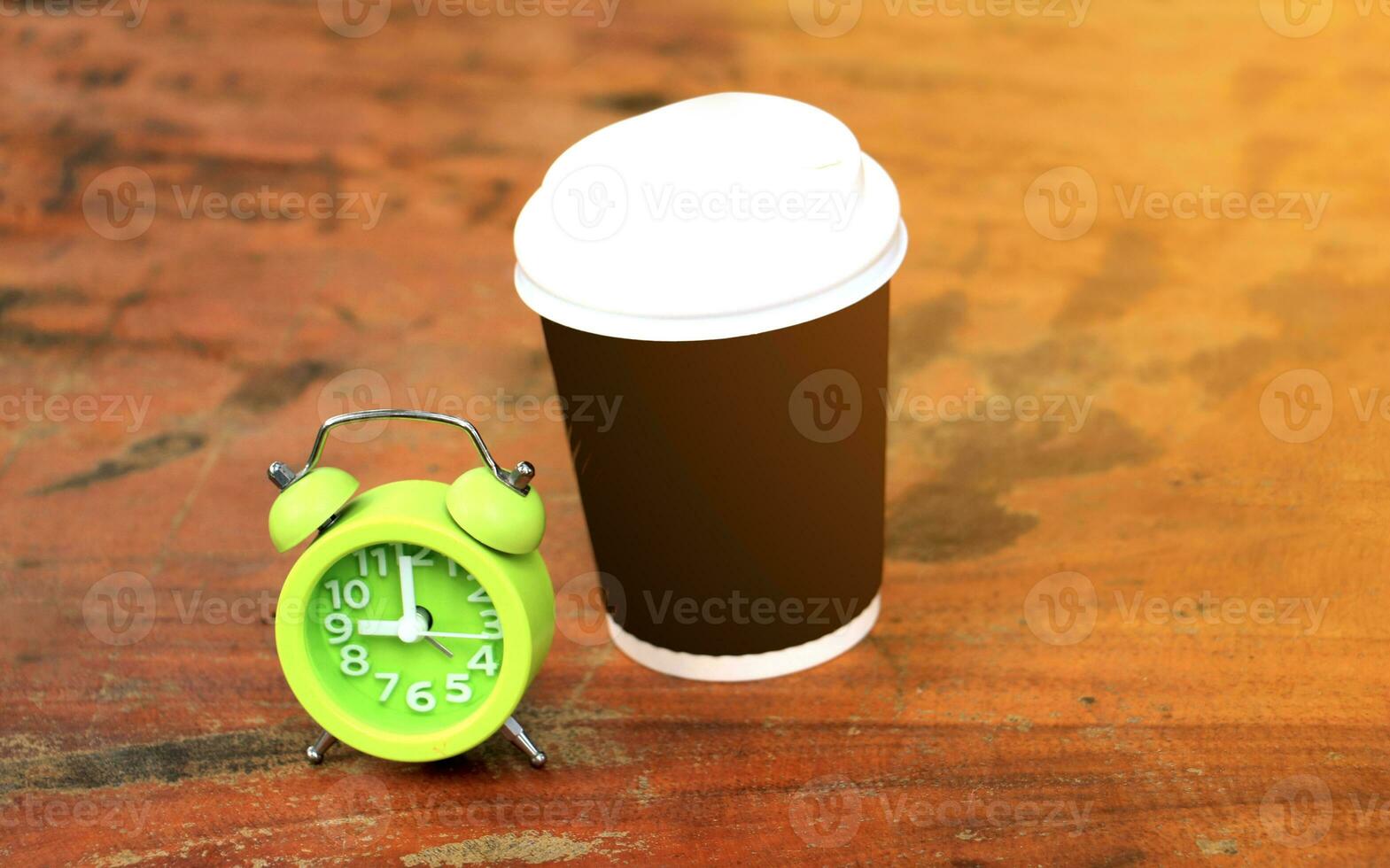 uma café copo e a alarme relógio em uma mesa foto