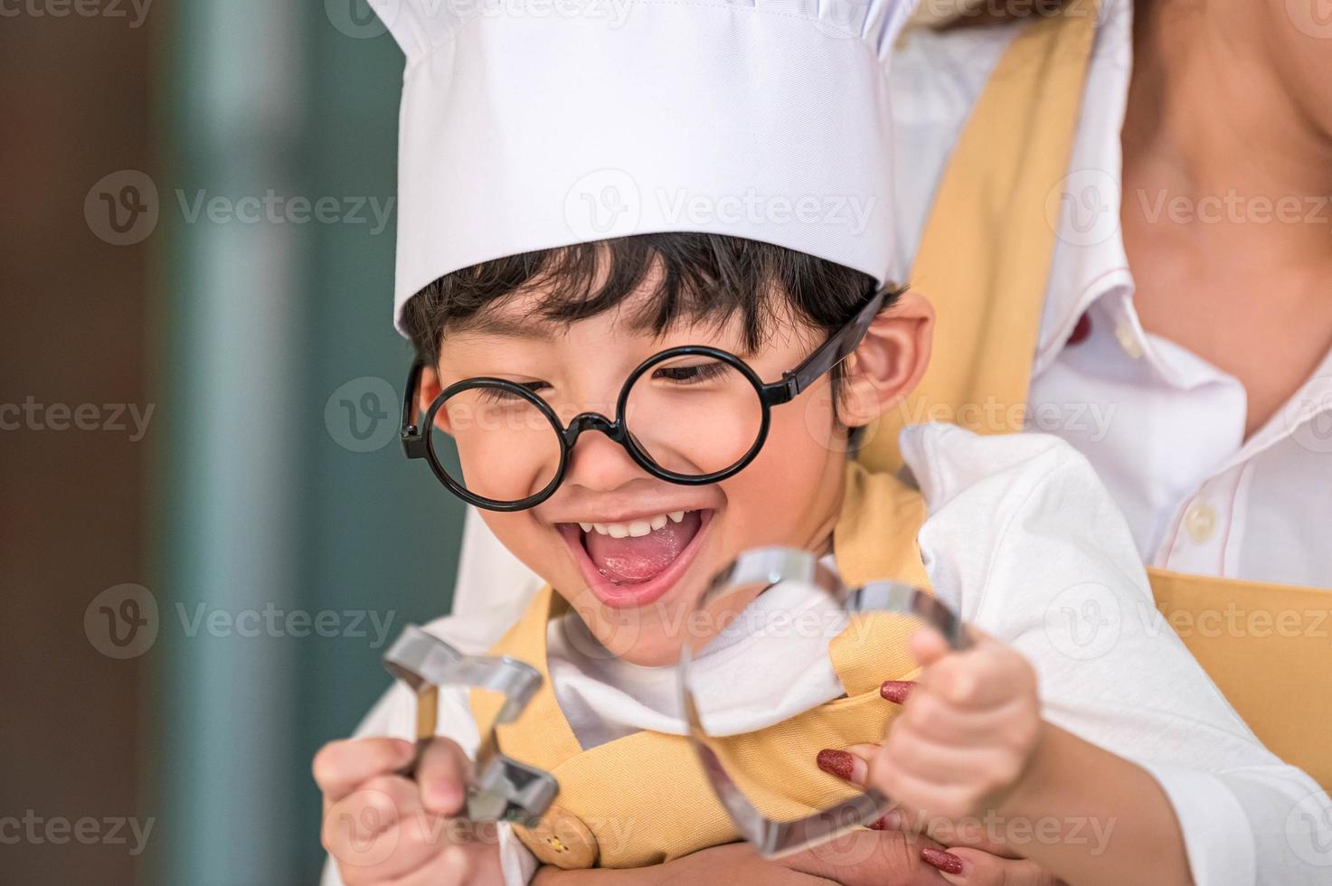 lindo garotinho feliz asiático interessado em cozinhar com a mãe engraçada na cozinha de casa. pessoas estilos de vida e família. conceito de comida e ingredientes caseiros. duas pessoas fazendo bolo de natal e biscoitos foto