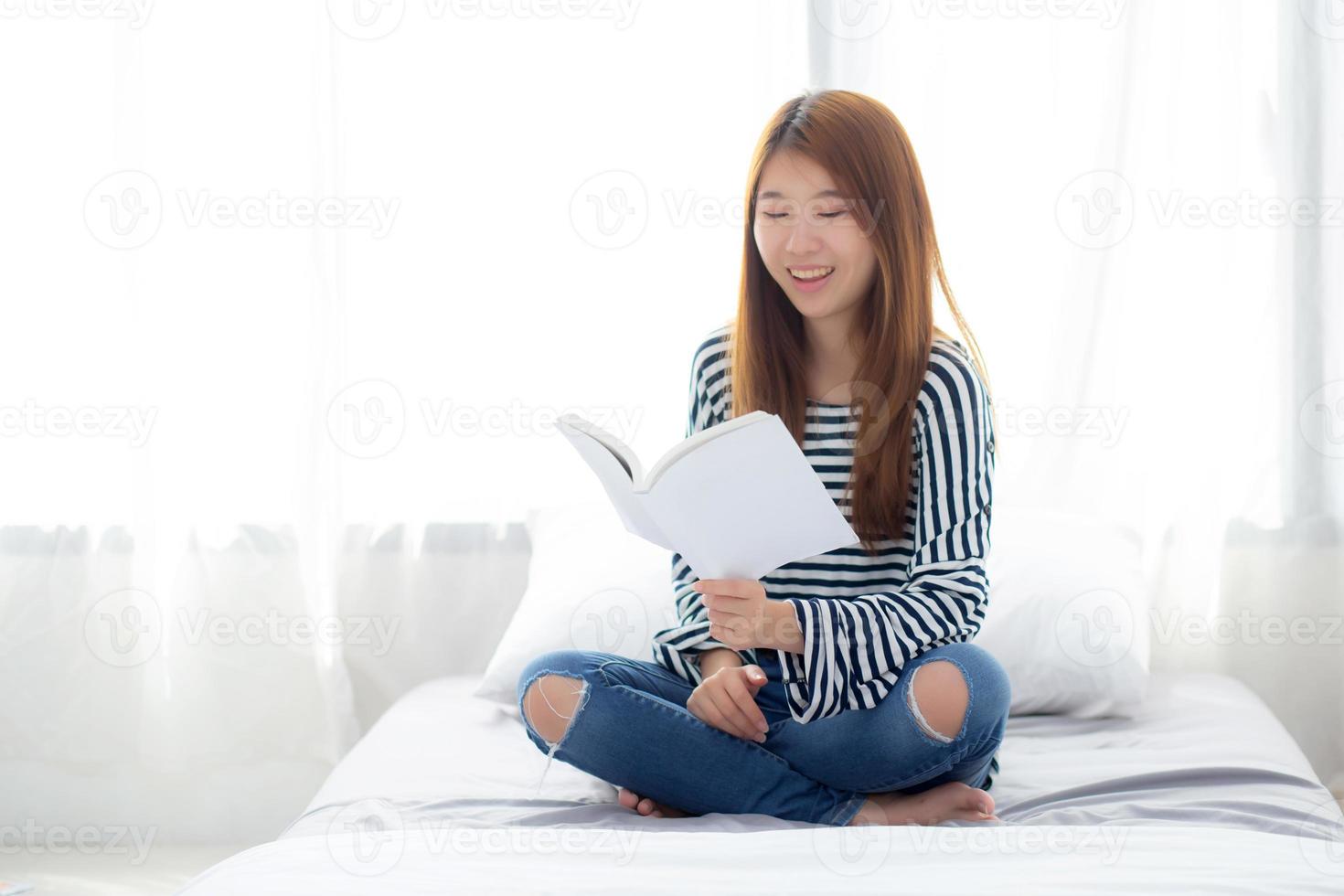 linda de uma jovem mulher asiática relaxar sentado lendo um livro no quarto. foto