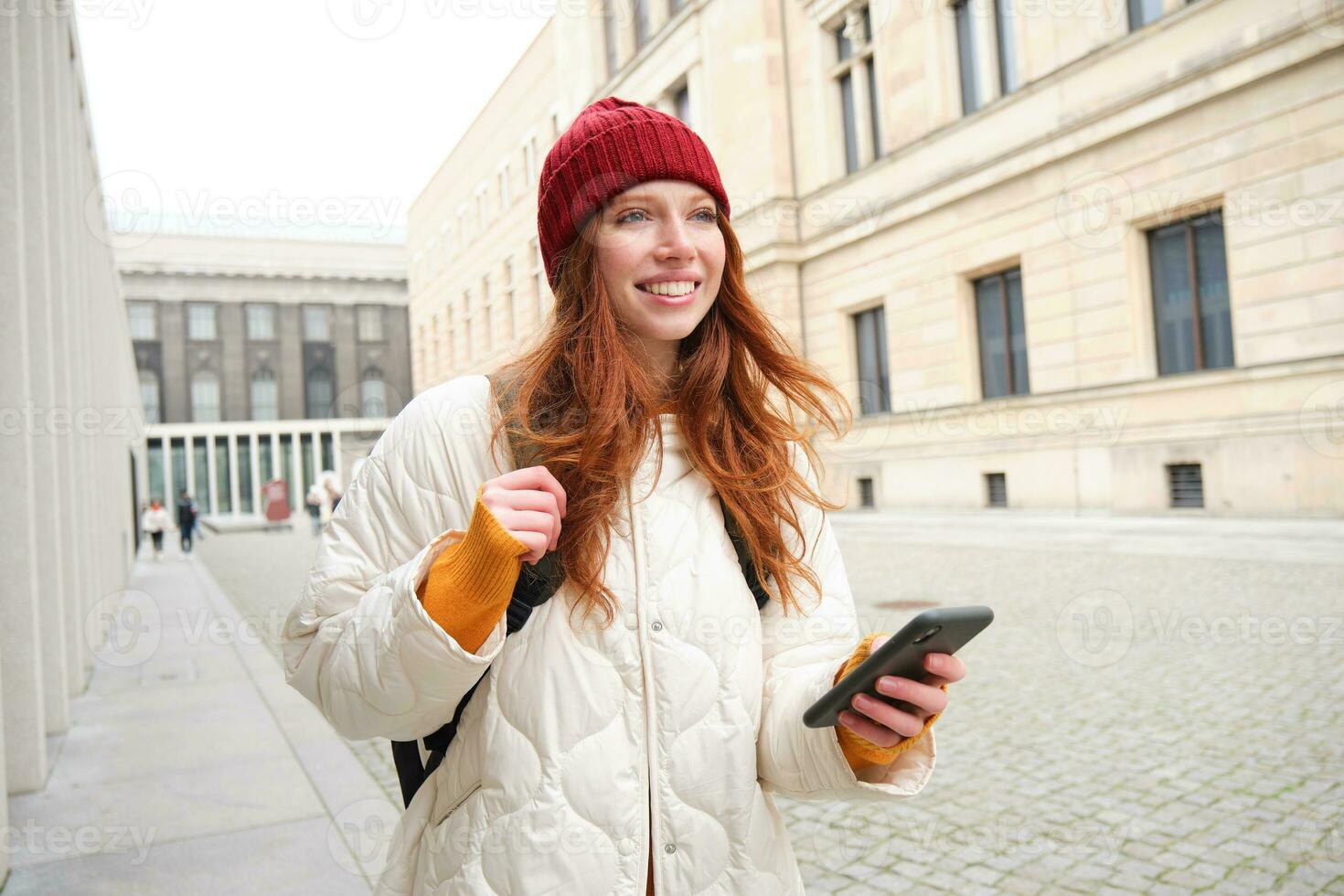 turismo e tecnologia. lindo ruiva menina turista, olhando para uma rota em aplicativo, usando cidade mapa em Smartphone, lendo sobre passeios turísticos lugares em Móvel telefone foto