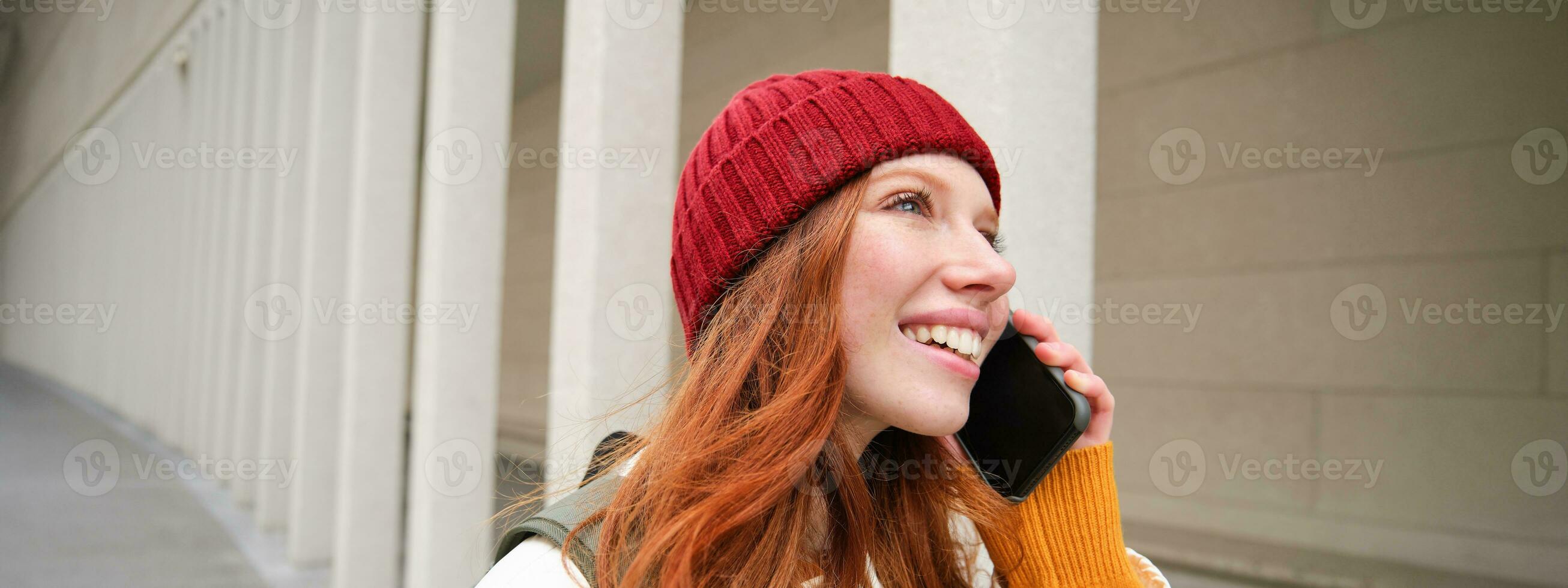 feliz ruiva mulher, menina com telefone fala, tem conversação em Móvel aplicativo, usa Internet para ligar no exterior com Smartphone aplicativo, rindo e sorridente foto