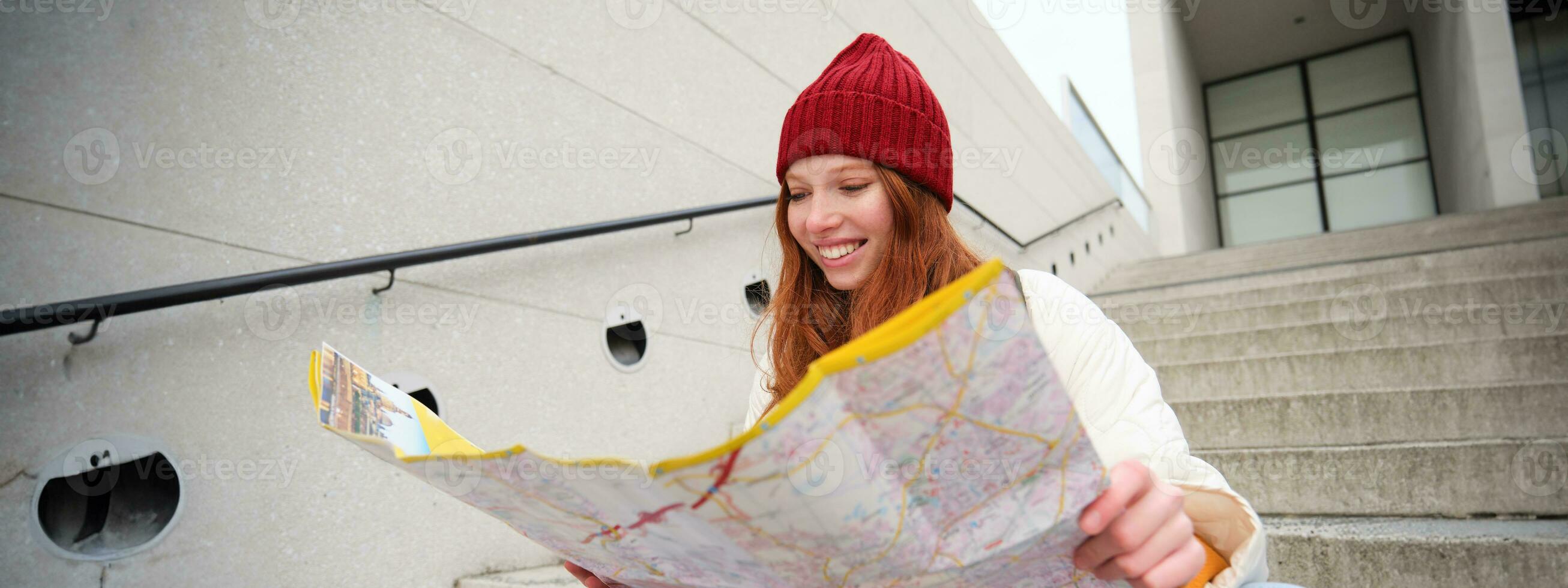 lindo menina turista senta em escadas com cidade mapa, planos dela jornada, parece para direção enquanto viajando por aí cidade, pesquisas rota para passeios turísticos foto