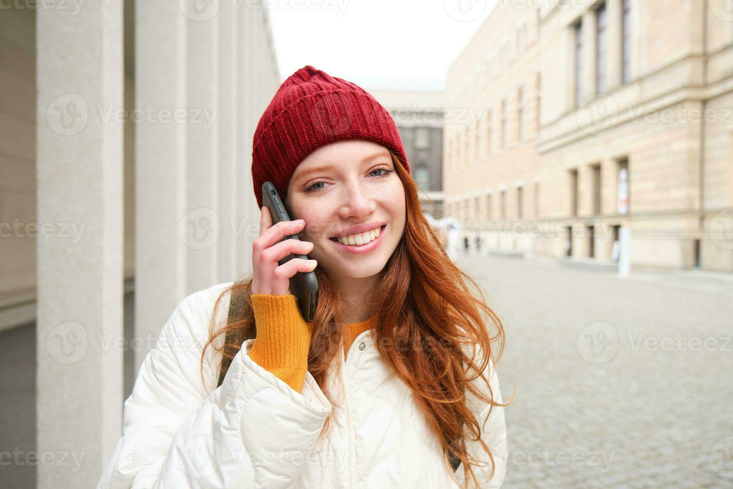 feliz ruiva mulher, menina com telefone fala, tem conversação em Móvel aplicativo, usa Internet para ligar no exterior com Smartphone aplicativo, rindo e sorridente foto