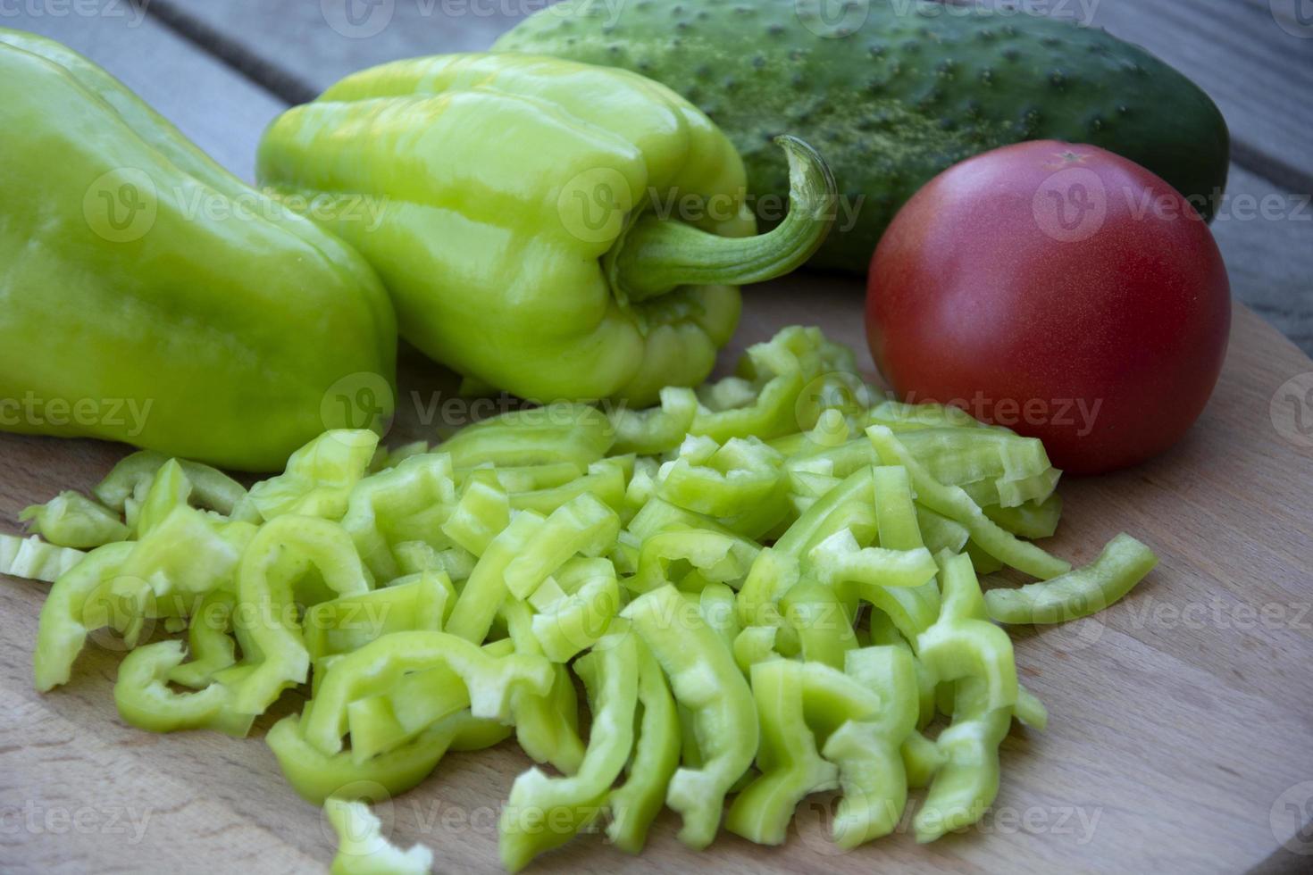 tomate vermelho, pepino e pimentão em tiras mentem sobre um fundo de madeira. colher legumes frescos da horta. foto