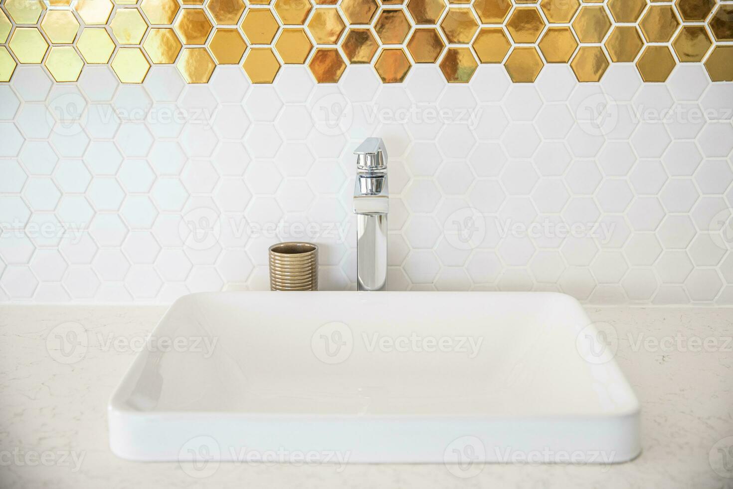 luxo branco porcelana Pia com ouro decoração em uma banheiro mesa dentro natural luz foto