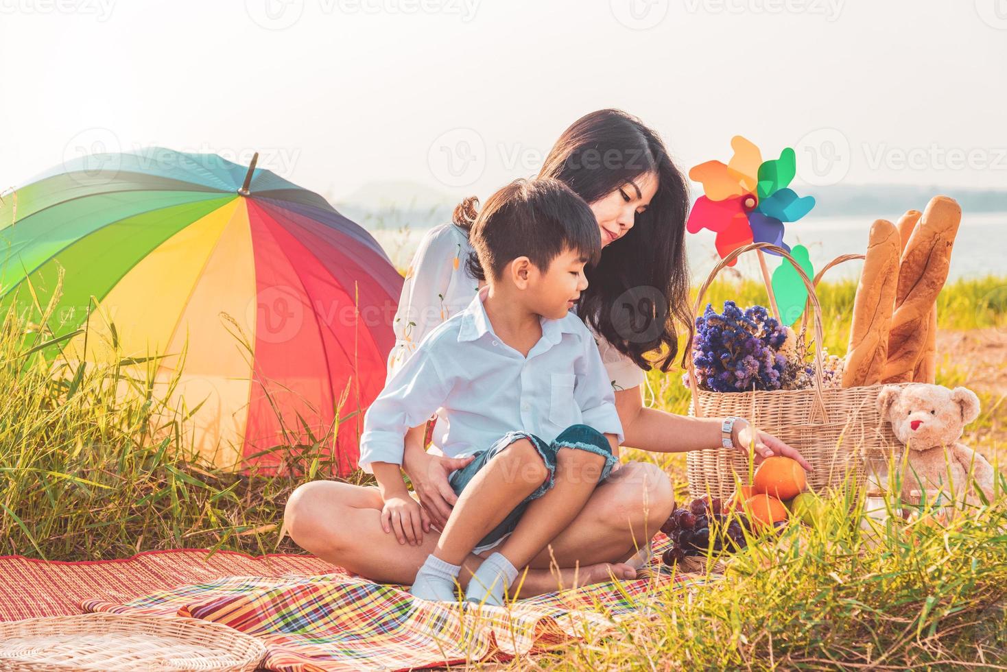 linda mãe asiática e filho fazendo piquenique e na festa de verão de Páscoa em Prado perto de lago e montanha. feriado e férias. estilo de vida de pessoas e conceito de vida familiar feliz. pessoa tailandesa foto