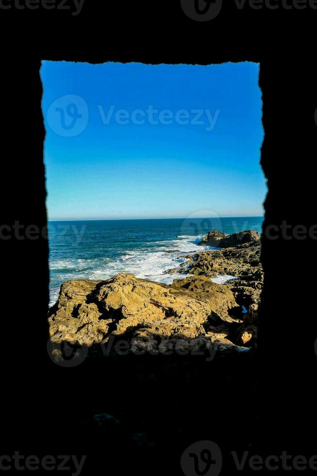 uma Visão do a oceano através uma janela em uma rochoso penhasco foto